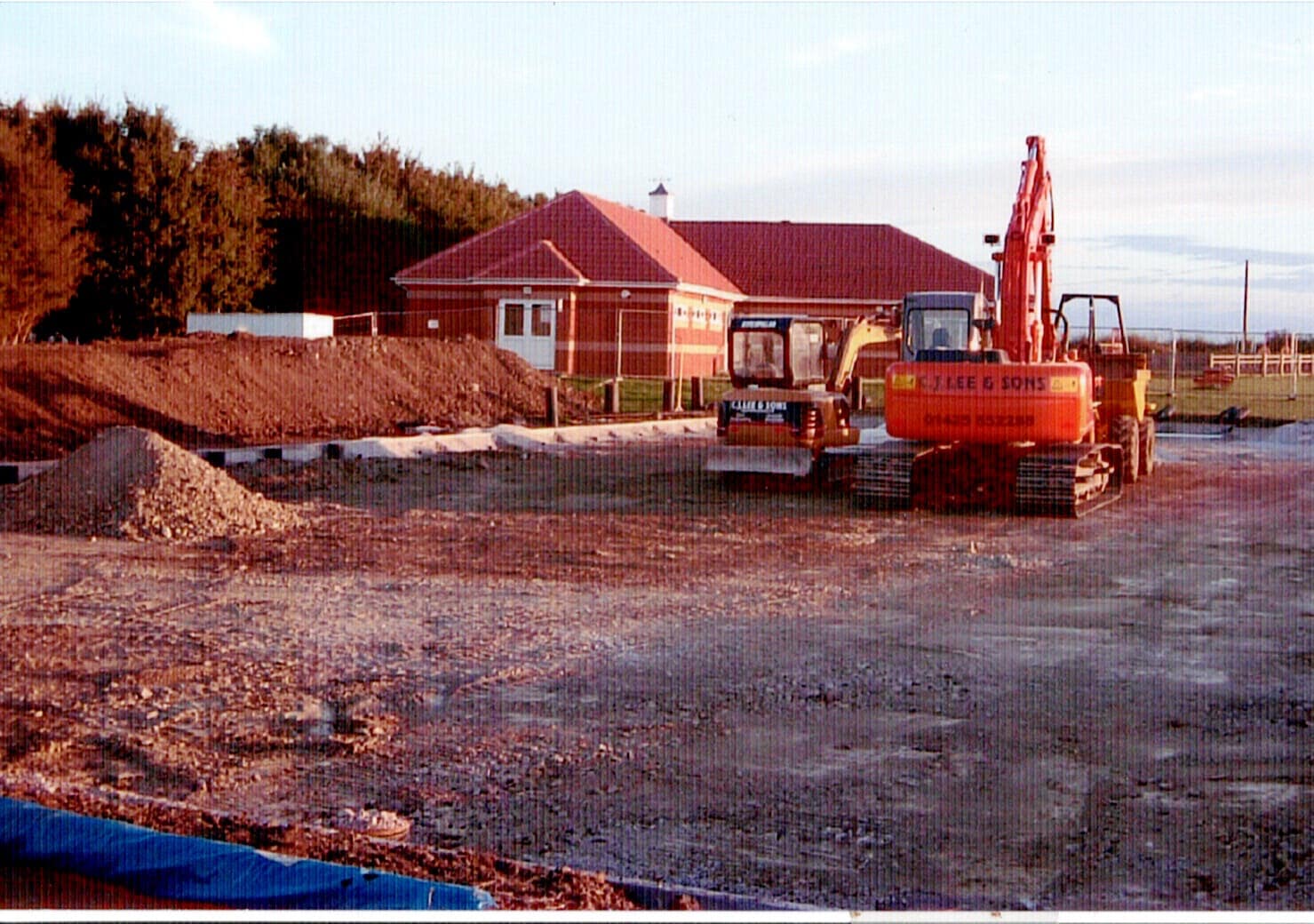 Diggers laying the base of the multi use games area with the clubhouse behind